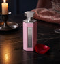 Flacon d'extrait de parfum Summer Pink de PDS SHOP, rose hexagonal sur table en marbre avec bougie et pétale de rose